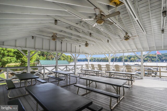 wooden terrace with a water view and ceiling fan
