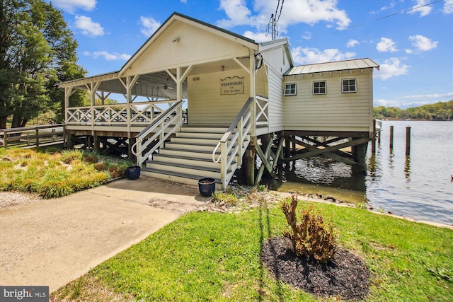 raised beach house with fence, a water view, and metal roof