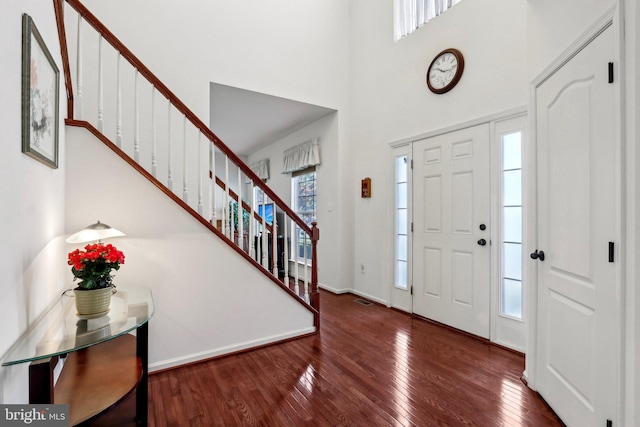 foyer featuring stairway, hardwood / wood-style floors, baseboards, and a high ceiling