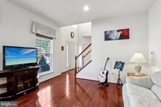 living area featuring visible vents, stairway, wood finished floors, and baseboards