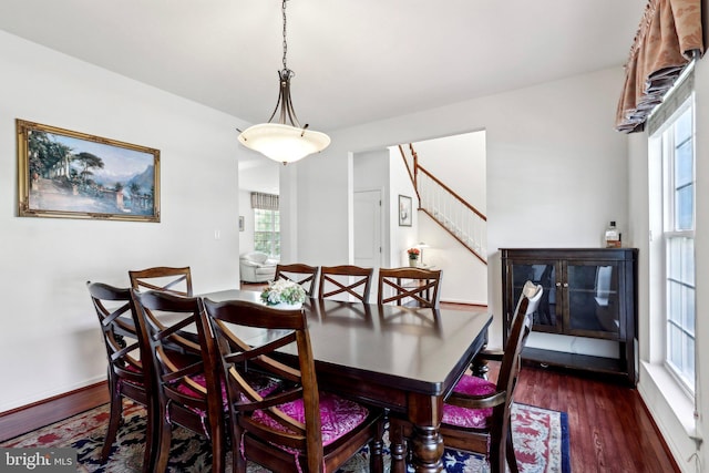 dining area with wood finished floors, baseboards, and stairs
