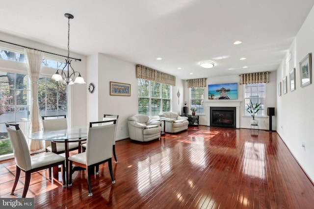 dining room with an inviting chandelier, a glass covered fireplace, hardwood / wood-style flooring, and recessed lighting