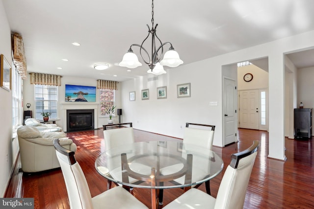 dining room with recessed lighting, a notable chandelier, wood finished floors, and a glass covered fireplace