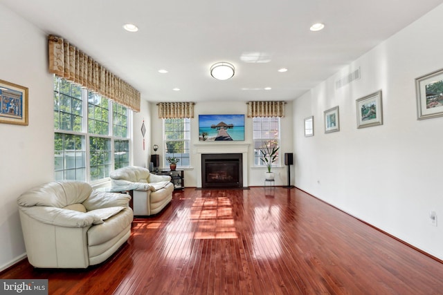 living area with a fireplace with flush hearth, visible vents, hardwood / wood-style floors, and recessed lighting