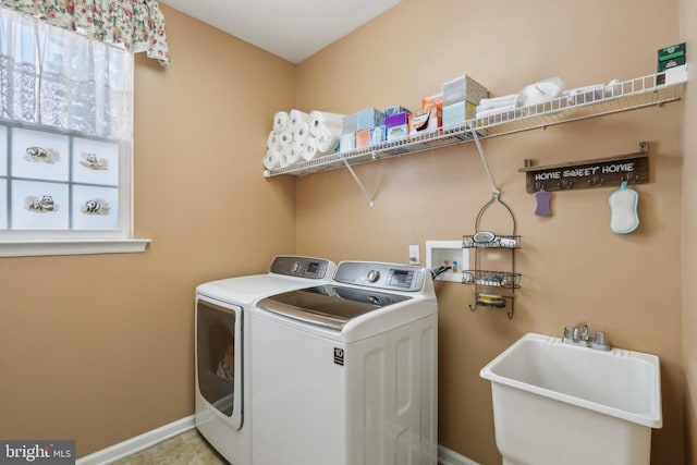 laundry area featuring baseboards, independent washer and dryer, laundry area, and a sink