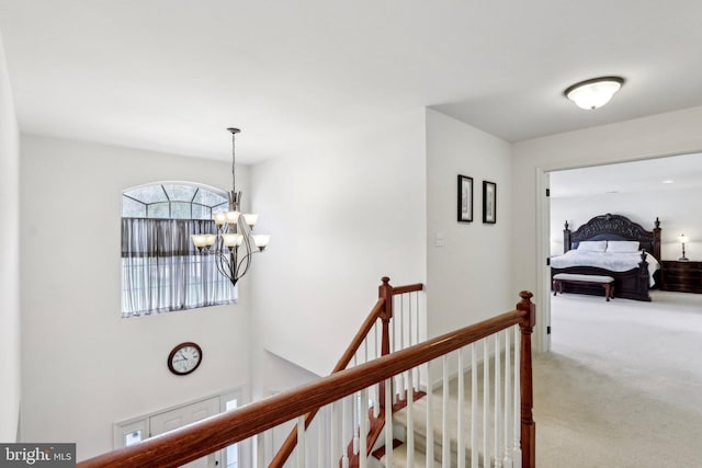 hallway with an upstairs landing, carpet, and a chandelier