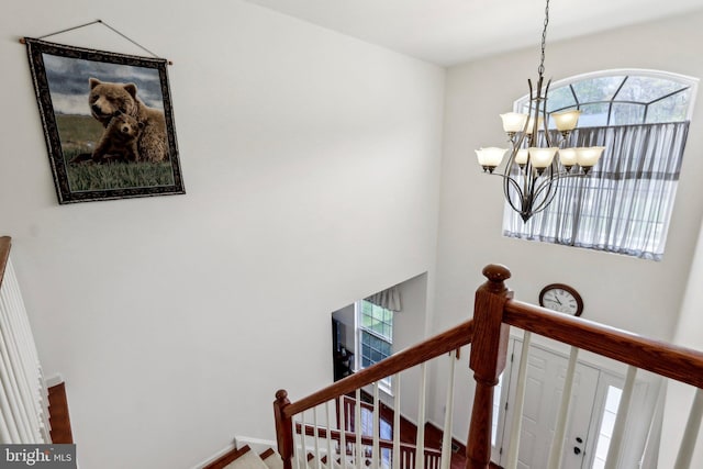 stairway featuring a notable chandelier and baseboards