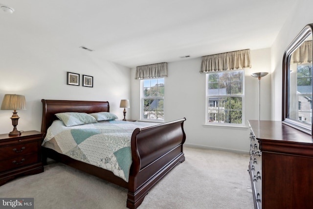 bedroom with baseboards, visible vents, and light colored carpet