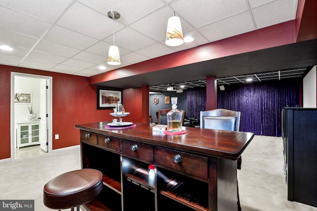 bar with baseboards, decorative light fixtures, carpet flooring, and a drop ceiling