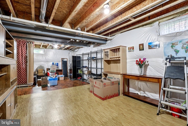 below grade area featuring freestanding refrigerator and wood finished floors