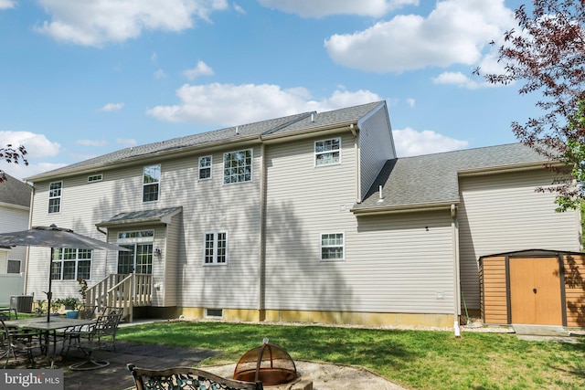 rear view of property featuring an outdoor structure, a storage unit, a patio area, an outdoor fire pit, and a yard