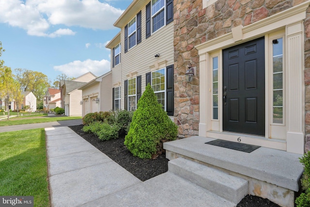 entrance to property with a residential view, a yard, and stone siding