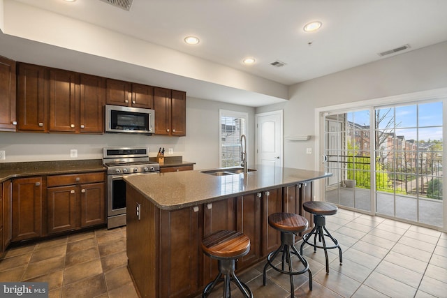 kitchen featuring visible vents, a sink, dark tile patterned flooring, and stainless steel appliances