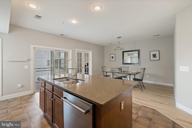 kitchen featuring stainless steel dishwasher, a sink, baseboards, and french doors