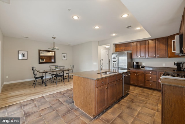 kitchen with a sink, appliances with stainless steel finishes, dark tile patterned flooring, and visible vents