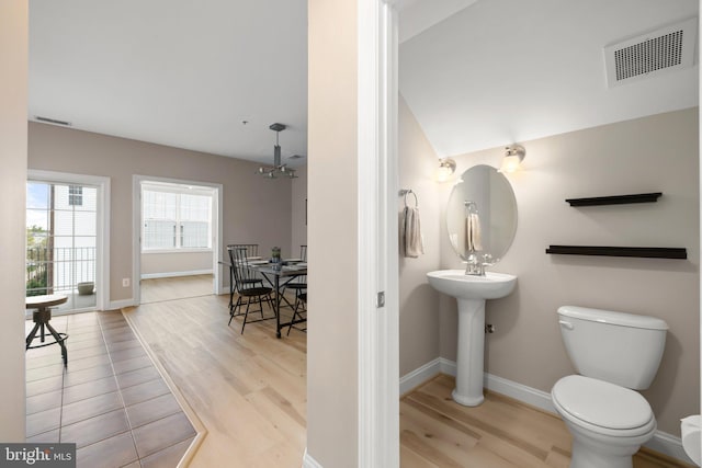 half bathroom with baseboards, toilet, wood finished floors, and visible vents