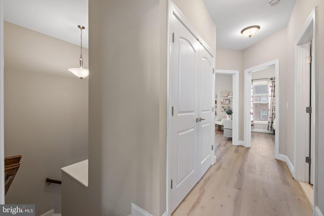 hall featuring baseboards and light wood finished floors