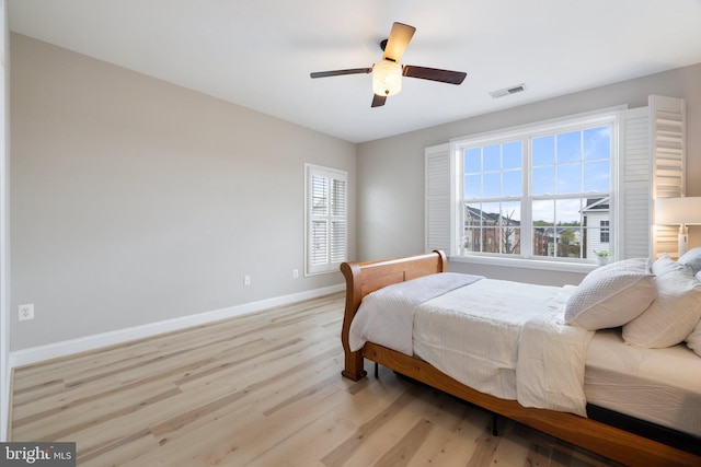 bedroom with baseboards, visible vents, multiple windows, and light wood-style flooring