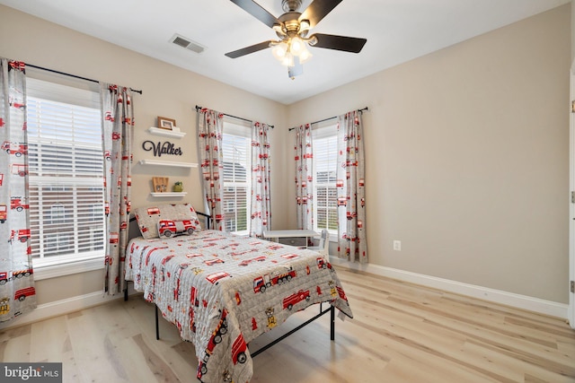 bedroom featuring baseboards, ceiling fan, wood finished floors, and visible vents