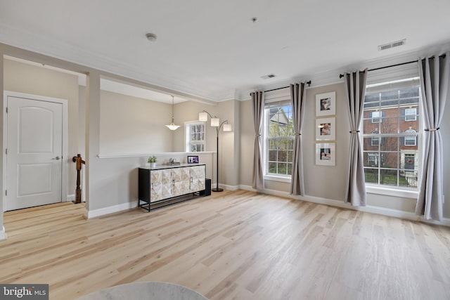 unfurnished living room featuring crown molding, baseboards, visible vents, and wood finished floors