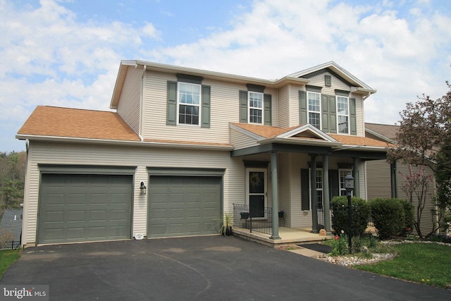 view of front of house with an attached garage, driveway, a shingled roof, and covered porch