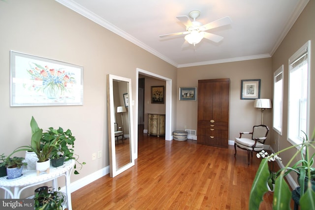 living area featuring light wood-type flooring, baseboards, and ornamental molding