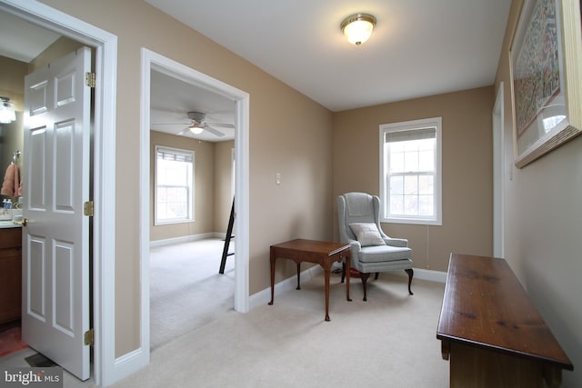 living area with baseboards, a healthy amount of sunlight, light colored carpet, and ceiling fan