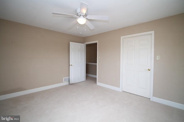 unfurnished bedroom featuring baseboards, a ceiling fan, visible vents, and light colored carpet