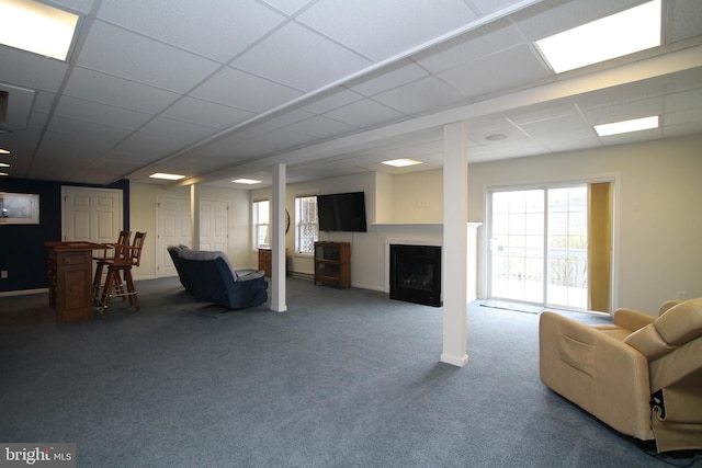 below grade area featuring a fireplace, a paneled ceiling, and carpet flooring