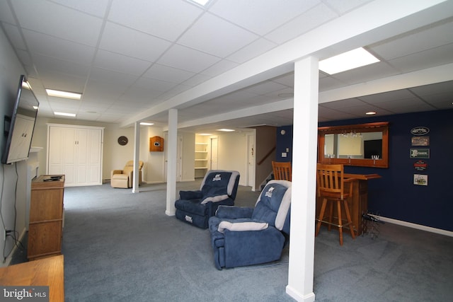 finished basement with carpet, a bar, and a drop ceiling