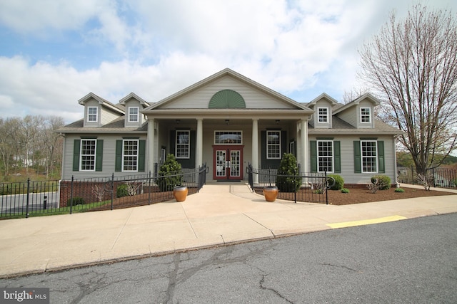 view of front of property featuring french doors, covered porch, and fence