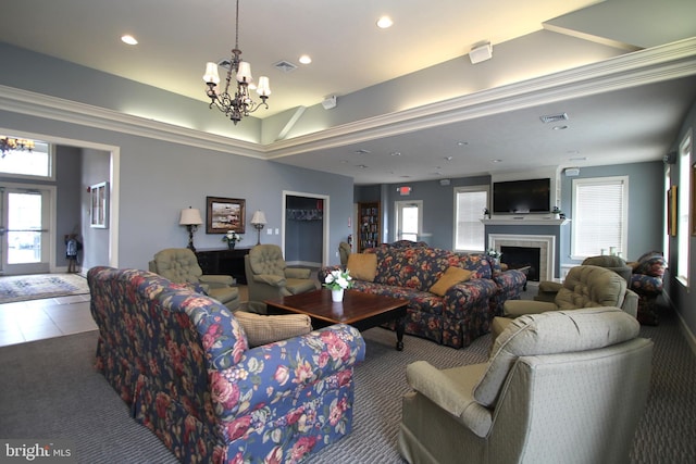 carpeted living area with a chandelier, plenty of natural light, and visible vents