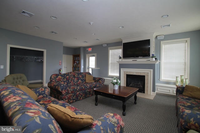 living room featuring a tile fireplace, visible vents, and carpet