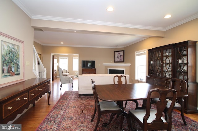dining room featuring stairway, a healthy amount of sunlight, wood finished floors, and a fireplace