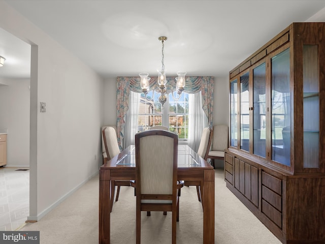 dining area with baseboards, light colored carpet, and a notable chandelier