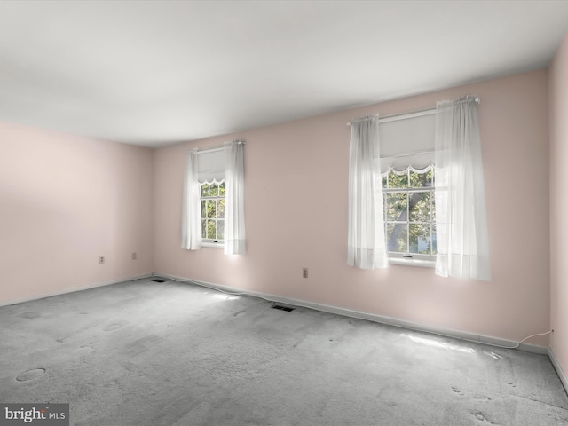 empty room featuring carpet floors, baseboards, and visible vents