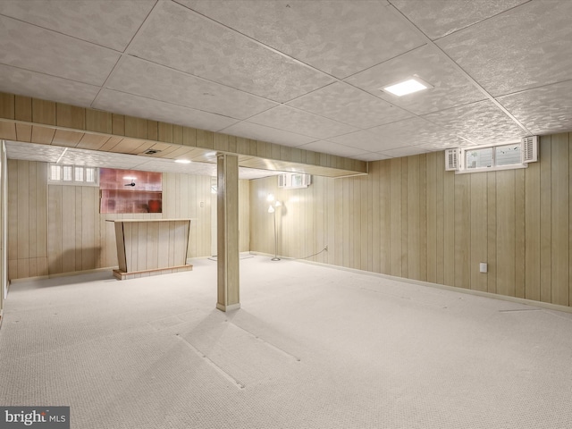 below grade area with wood walls, a wealth of natural light, a bar, and carpet