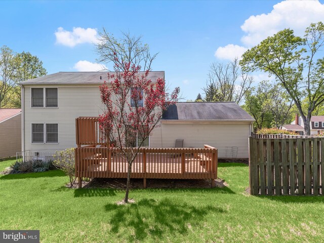 rear view of house with fence, a yard, and a deck
