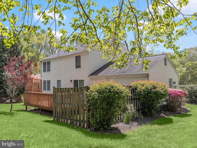 rear view of property with a lawn, a shingled roof, and a deck