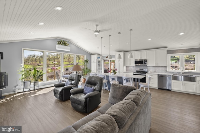 living room featuring recessed lighting, lofted ceiling, wood finished floors, a ceiling fan, and a wall mounted AC