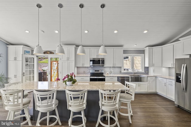 kitchen featuring tasteful backsplash, white cabinetry, a center island, and stainless steel appliances