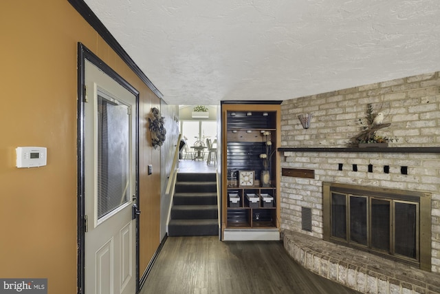 interior space with wood finished floors, visible vents, ornamental molding, a fireplace, and a textured ceiling