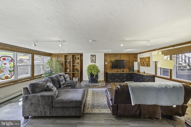 living area with a baseboard radiator, wood finished floors, and rail lighting