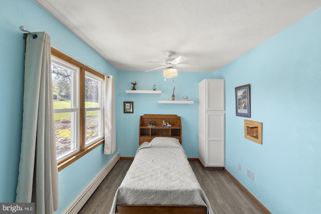 bedroom with a baseboard heating unit, baseboards, a ceiling fan, and wood finished floors