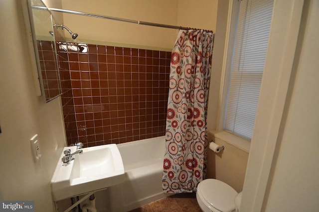 bathroom with shower / bath combo, a sink, and toilet