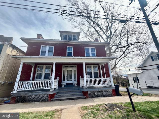 american foursquare style home featuring covered porch and a chimney