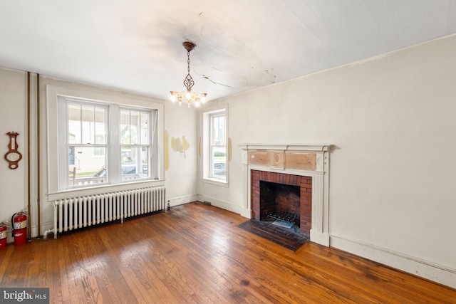 5342 Main St, Stephens City, VA 22655 - unfurnished living room with radiator heating unit, a chandelier, hardwood / wood-style floors, and a brick fireplace