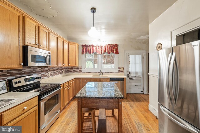 5342 Main St, Stephens City, VA 22655 - kitchen featuring stainless steel appliances, light wood-type flooring, decorative backsplash, pendant lighting, and a sink