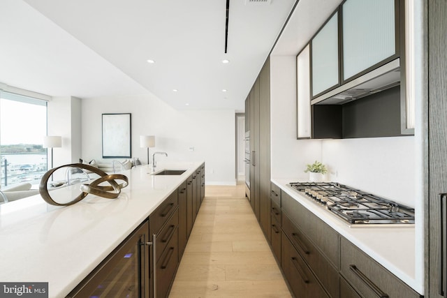 601 Wharf St SW Unit 502, Washington, DC 20024 - kitchen featuring a sink, light wood-type flooring, dark brown cabinets, wine cooler, and stainless steel gas cooktop