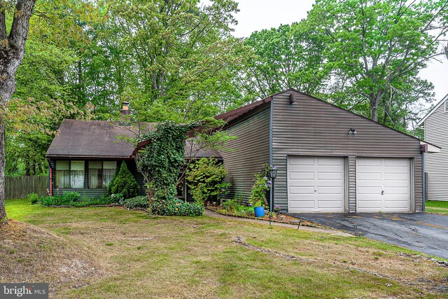 mid-century home featuring a garage, asphalt driveway, and a chimney